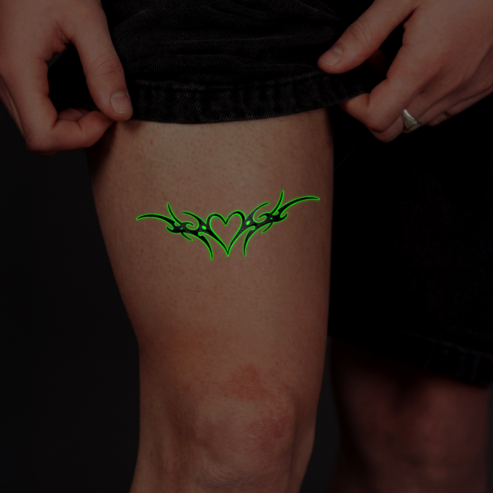 Green tribal tattoo on a person's leg with black shorts.