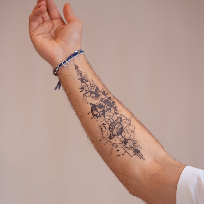 Arm with a tattoo of celestial designs on a plain background