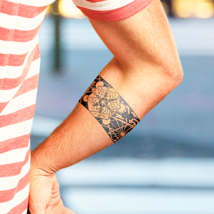 Person wearing a black temporary tattoo on their arm with a blurred background