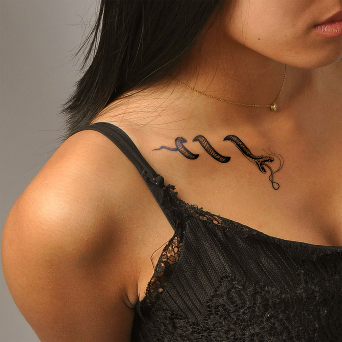 Woman with a snake tattoo on her neck against a neutral background
