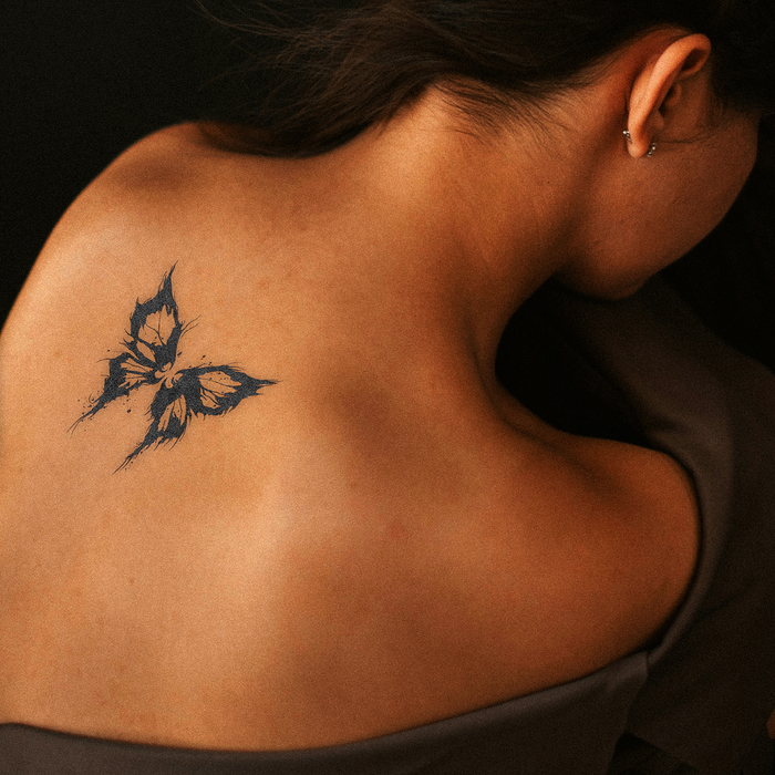 Butterfly tattoo on a person's shoulder against a dark background