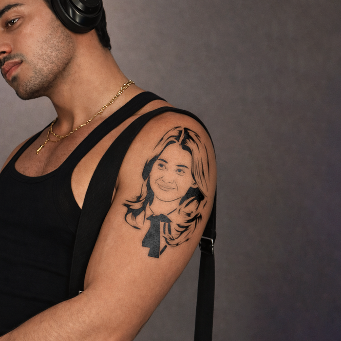 Man with a tattoo of a woman's face on his arm against a gray background