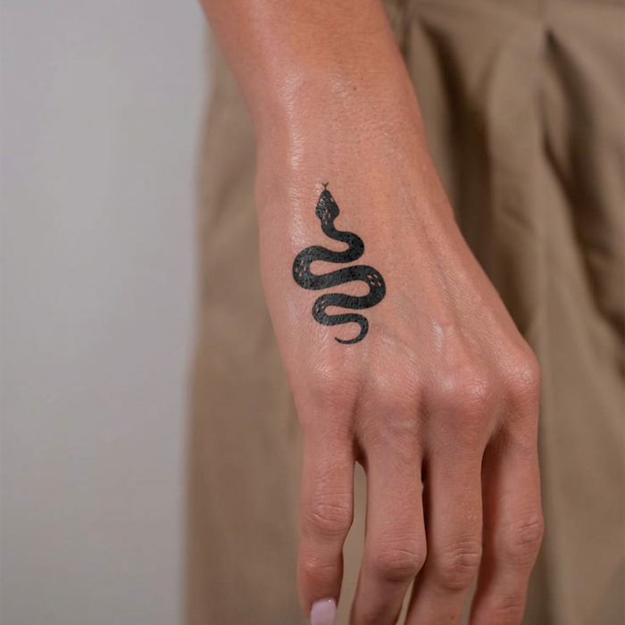 Hand with a black snake tattoo on a plain background