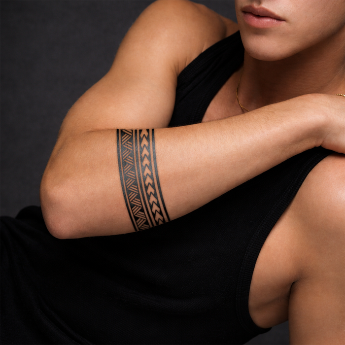 Person wearing a black sleeveless top with a tribal arm tattoo on a dark background